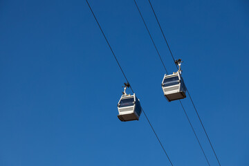 Obraz premium A pair of sky lift cabins in front of a clear blue sky. Tbilisi, Georgia.