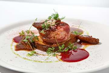 Baked camembert in parma ham on brioche with berry jam. Elegant food - hot appetizer of camembert and ham in summer menu. Cheese appetizer in fine dining. Summer menu.
