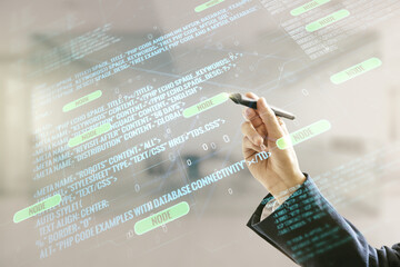 Man hand with pen working with abstract virtual coding illustration on blurred office background, software development concept. Multiexposure