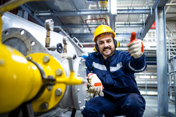 Portrait of petroleum refinery worker holding thumbs up in gas distribution center.