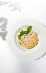 Traditional russian food - beef stroganoff with mushroom sauce and mashed potatoes. Beef stroganoff in white plate on light background with hard shadows. Stew meat with creamy sauce on summer menu.