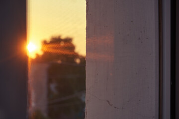 The sun in the golden hour, the sunset view. Window opening, selective focus, glare and reflection through glass