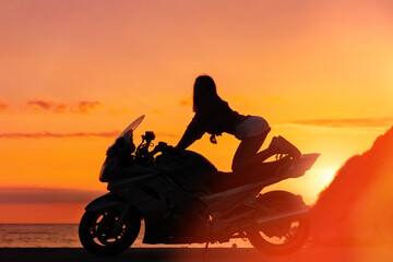 Fototapeta na wymiar Silhouette of sexy young woman posing on the motorcycle. Golden sunset and motorbike on the background. Concept of World Motorcyclist Day and moto trips