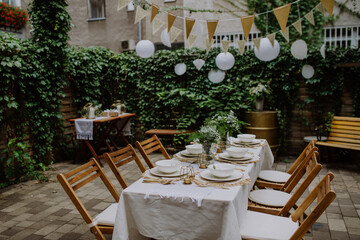 Festive wedding table setting with flowers at small reception in backyard in summer.