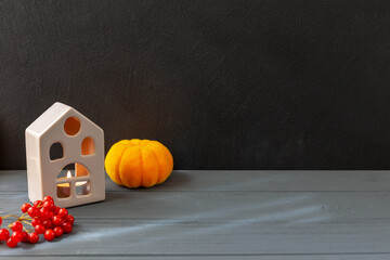 Halloween. On a black and gray background stands a house, a pumpkin and Viburnum berries