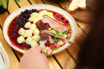 Duck breast served with kopytka, Polish potato dumplings, glazed beetroot and blackcurrant emulsion, selective focus.