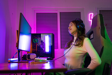 Fototapeta na wymiar Young people Backache. Gamer and E-Sport online of Asian woman playing online computer video game with lighting effect, broadcast streaming live at home. She a backache due to sitting for a long time