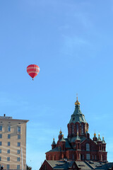 Fototapeta na wymiar Hot air balloon above the church on a sunny day photographed from the sea