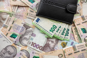 leather puse full in euro banknotes lying on ukraine money uah hryvnia, exchange concept.