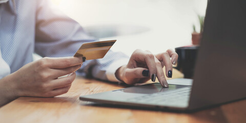 Hands holding credit card, typing on the keyboard of laptop, onine shopping detail close up