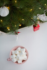 Fototapeta na wymiar Mug with marshmallow near Christmas tree