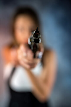 beautiful brunette sexy woman with a gun in her hand directed it at the victim.