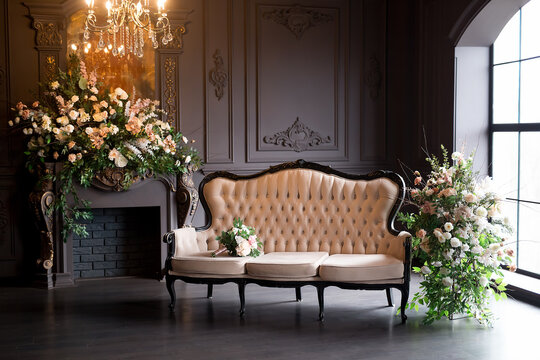 Black room interior with a vintage sofa, chandelier, mirror and fireplace decorated with flowers