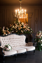 Black room interior with a vintage sofa, chandelier, mirror and fireplace decorated with flowers
