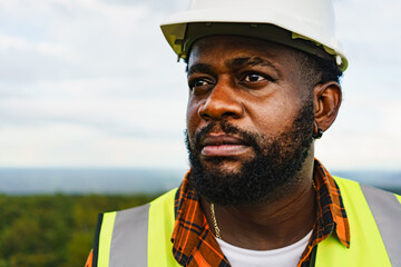 Close up portrait of black engineer man with serious face expression while working outdoor.