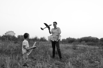 Monochrome photo. Little boy and his mom launches toy airplanes. Young aviator. The boy dreams of becoming an airplane pilot.