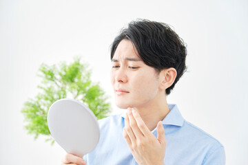 自宅で鏡で顔をチェックする男性