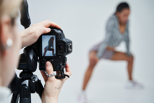 Photographer standing at the studio and making photo session for her multiracial model