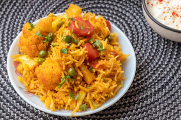 Vegetable pulao recipe with curd made with basmati rice and mix vegetables served in a round plate
