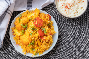 Vegetable pulao recipe with curd made with basmati rice and mix vegetables served in a round plate
