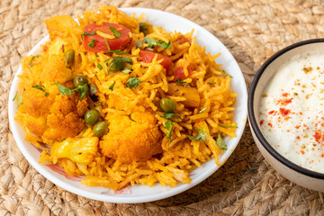 Vegetable pulao recipe with curd made with basmati rice and mix vegetables served in a round plate
