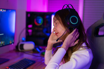 Young people Backache. Gamer and E-Sport online of Asian woman playing online computer video game with lighting effect, broadcast streaming live at home. She a backache due to sitting for a long time