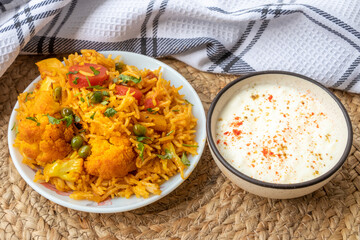 Vegetable pulao recipe with curd made with basmati rice and mix vegetables served in a round plate

