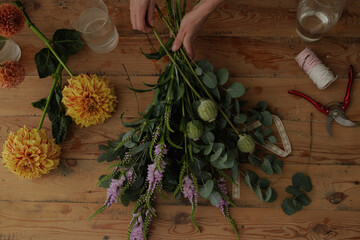 girl florist collects a bouquet in a flower workshop on a dark background. layout for floristry