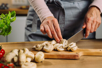 woman chopping mushrooms in kitchen - Powered by Adobe