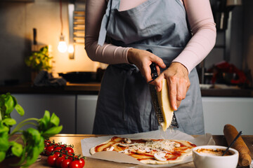 woman grater cheese on pizza in kitchen