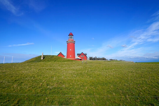 famous Bovbjerg Fyr lighthouse on the North Sea coast of Denmark in perfect light in front of a blue sky with some clouds at the horizon, high quality image, landmark, travel, tourism, attraction	