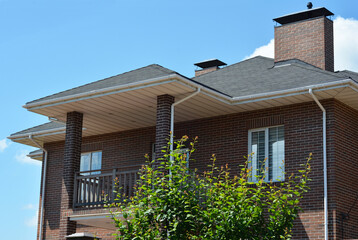 Brick house with asphalt shingles roof, chimney, balcony, rain gutter pipeline and soffit boards....