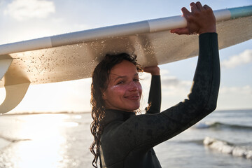Caucasian young woman with protective SPF 50 sunscreen at her face preparing to riding waves