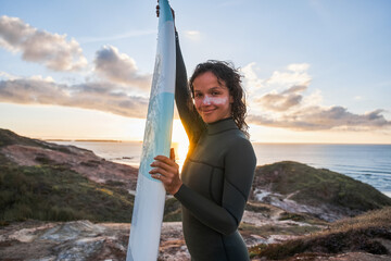 Strong young surf woman in contemplative mood smiling to the camera