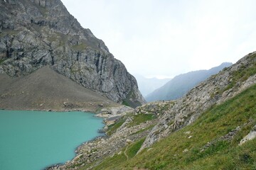 Lake Ala-Köl (Ala-kol, Ala-kul) in Tien Shan mountains in west of Kyrgyzstan, Asia. Cyan color of lake under steep mountaines. Touristic destination for trekking.