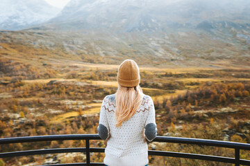Autumn travel outdoor woman looking at view forest and mountains in Norway healthy lifestyle sweater and hat clothing cold scandinavian weather tourist exploring Jotunheimen park - obrazy, fototapety, plakaty