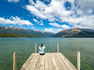 Fototapeta na wymiar A girl is taking photos of Kerr Bay at Lake Rotoiti in Nelson Lakes National Park, New Zealand.