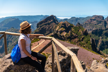Naklejka premium A tourist sitting looking at the mountains in the mountains at Pico do Arieiro, Madeira. Portugal
