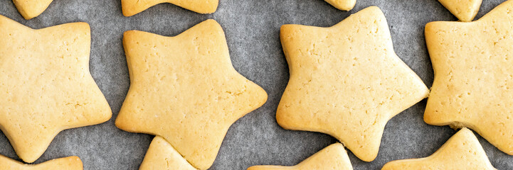 Baked shortbread star cookies on parchment paper banner. Wide panoramic header. Selective focus