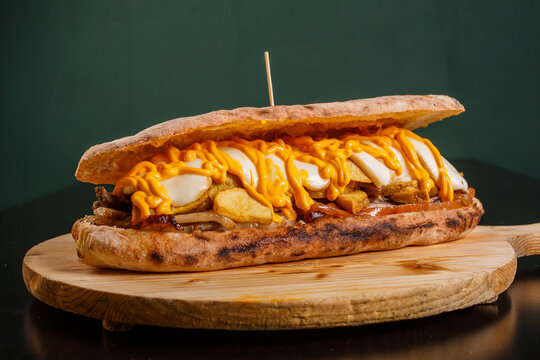 Panuozzo napoletano cotto nel forno a legna con patate al forno, porchetta, provola e cheddar fuso