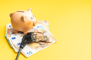 Electric plug, piggy bank and euro money. Concept of increasing electricity prices.