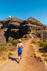 A young woman walking towards Pico do Arieiro from Ninho da Manta viewpoint, Madeira. Portugal