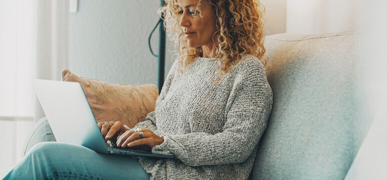 Horizontal Banner Image With Young Mature Woman Using Laptop Sitting On The Sofa. Concept Of Surfing The Web People. Modern Female Working On Computer At Home In Relax Time. Lady Use Notebook Happy