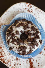 Ciambella al cioccolato, ricoperta di cioccolato bianco e biscotti sbriciolati fotografata dall'alto