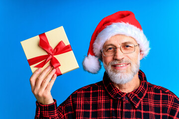 Handsome senior bearded man holding gift box and wish a Merry Christmas and a happy new year