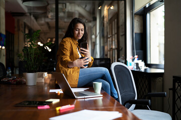 Young businesswoman drinking coffee in her office. Woman enjoy in coffee break.