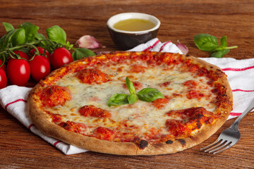 Thin pizza with tomato sauce, cheese and basil on a wooden background