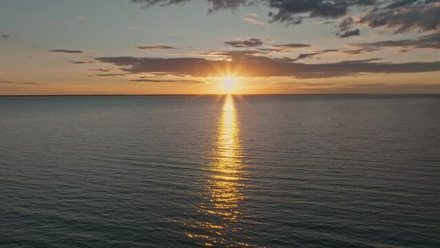 Tropical golden sunset over ocean water slow motion aerial view. Sun setting reflection on seascape. No-people sand beach at sea bay. Calm waterscape at sunny evening. Summer vacation.