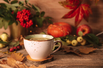 Obraz na płótnie Canvas A cup of hot tea with lemon on an autumn background. Autumn and fall postcard. Thanksgiving day or halloween concept.