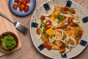 Spicy fried egg salad with vegetables, tomatoes, onions